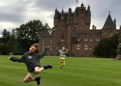 two children jumping in front of castle